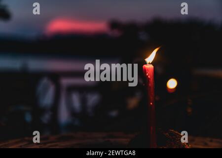 Eine einzelne rote Kerze brennt im tropischen Sonnenuntergang von kambodscha Stockfoto