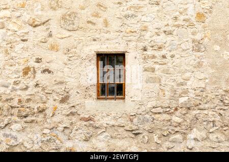 Minimalistisches Foto eines Schlossfensters, das in einer Steinmauer eingeschlossen ist. Stockfoto