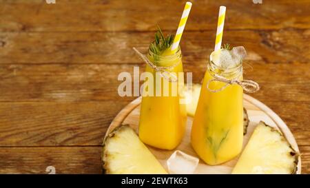 Frisch zubereitetes Ananassaft mit Eis in einem kleinen Glas Flasche auf Holzhintergrund Stockfoto