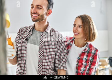 Erfreulicher Mann, der die Wand mit einer Malrolle bemalte Stockfoto