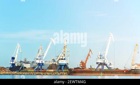 Arbeitskrane mit Frachtschiff, Lastkahn auf Verladung in der Werft am Sonnentag, Toning, selektiver Fokus Stockfoto