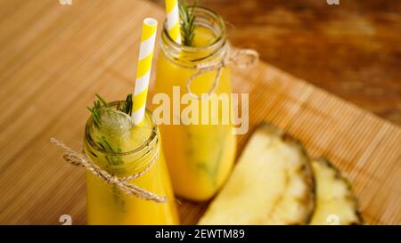 Frisch zubereitetes Ananassaft mit Eis in einem kleinen Glas Flasche auf Holzhintergrund Stockfoto