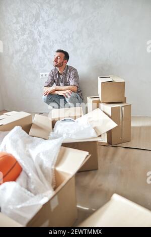 Netter junger Mann, der sich in seiner neuen Wohnung glücklich fühlt Stockfoto