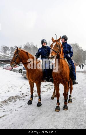 Zwei finnische Polizisten reiten auf ihren Pferden in der Nähe eines Stadtparks in Helsinki, Finnland Stockfoto