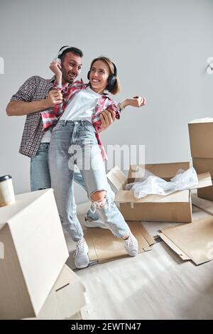 Fröhliche Frau und ihr Mann tanzen in ihrer neuen Wohnung Stockfoto