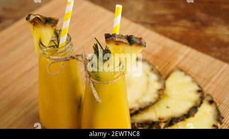 Frisch zubereitetes Ananassaft mit Eis in einem kleinen Glas Flasche auf Holzhintergrund Stockfoto