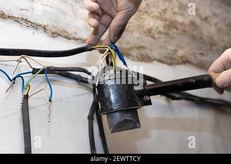 Ein Elektriker löt verdrehte elektrische Drähte in einem Haus im Bau. Anschluss und Verdrehen der Kabel. Stockfoto