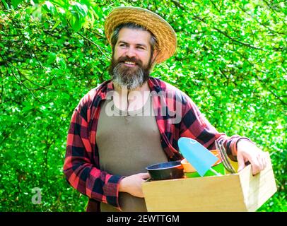 Professioneller Gärtner im Frühlingsgarten. Bärtiger Mann mit Gartengeräten Pflanzen. Stockfoto