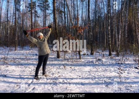 Ältere Frau, die beim Nordic Walking mit Stöcken trainiert Winterwald Stockfoto