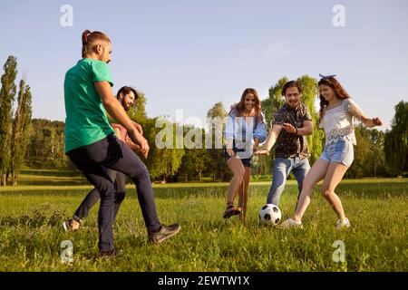 Glückliche Freunde haben Spaß beim aktiven Spielen im Park auf der grünen Wiese. Stockfoto