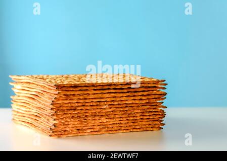 Matzah auf weißem Tisch über blauem Hintergrund.Matza -Jüdisches traditionelles Passah ungesäuertes Brot. Pesach Feier Symbol. Stockfoto