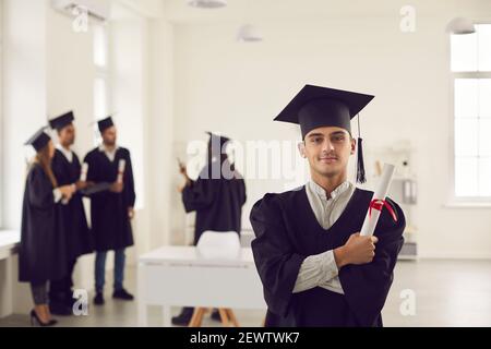 Selbstbewusster und stolzer Student in Form eines Hochschulabsolventen und mit einem Diplom in der Hand. Stockfoto