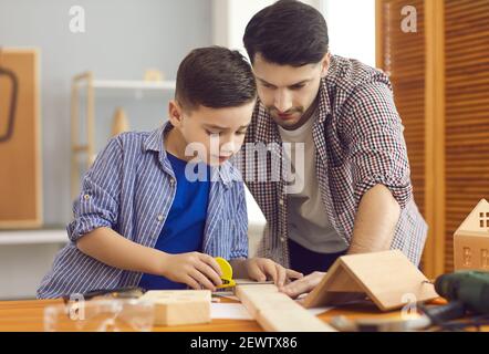 Glücklich konzentrierten Vater und Sohn Messung hölzerner Details für die Herstellung Vogelhaus Stockfoto