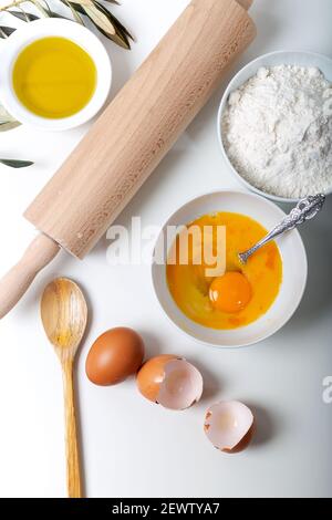 Lebensmittelzutaten für Backwaren oder hausgemachte Brot oder Pasta, Olivenöl, Mehl, Eier auf weißem Hintergrund. Draufsicht auf Teig und Backzutaten isoliert Stockfoto