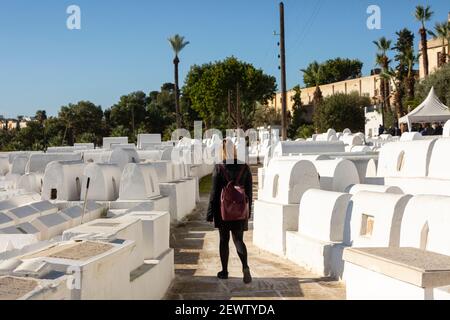 Eine weibliche Touristin, die zwischen weißen Gräbern auf dem jüdischen Friedhof im jüdischen Viertel (Mellah) von Fes el-Jdid, Marokko, läuft Stockfoto