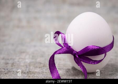 Hähnchenei in lila Bow-Knoten gewickelt. Gesunde Rohkost. osterei, präsent. Stockfoto