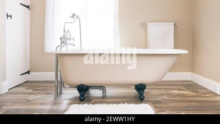 Moderne Einrichtung im Bad mit Badewanne mit Clawfoot und Bodenfliesen. Luxuriöse, moderne Badezimmer, Großbritannien. Stockfoto