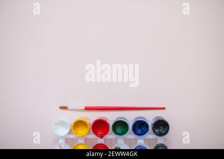 Helle Farben und zwei Pinsel auf einem hellrosa Hintergrund. Vorbereitung für das Zeichnen Stockfoto