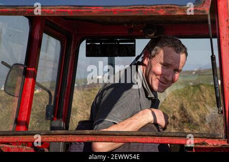 Irischer Bauer in rot Massey Ferguson 35X Tractor, County Kerry, Irland Stockfoto