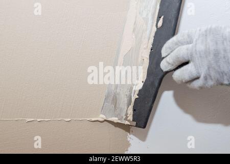 Hand des Bauarbeiters Verputzen an der Wand.Sanierungsarbeiter Hand Verputzen Die Wand.Bau Finishing Works.Work richtet sich mit einer Spachtelwand Stockfoto
