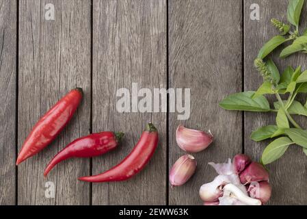 Rote Chilischoten und andere Gewürze über Holztisch mit Kopieplatz. Stockfoto