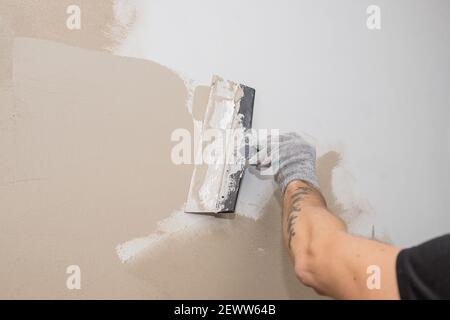 Hand des Bauarbeiters Verputzen an der Wand.Sanierungsarbeiter Hand Verputzen Die Wand.Bau Finishing Works.Work richtet sich mit einer Spachtelwand Stockfoto