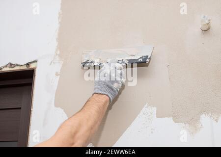 Hand des Bauarbeiters Verputzen an der Wand.Sanierungsarbeiter Hand Verputzen Die Wand.Bau Finishing Works.Work richtet sich mit einer Spachtelwand Stockfoto