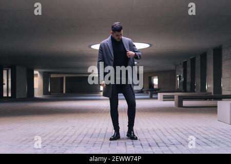 Hübscher junger Geschäftsmann, der seinen Mantel aufhängt und steht. Stockfoto