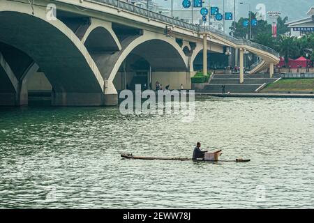 Guilin, China - 11. Mai 2010: Flaches Floß mit Fischer auf grünem Wasser Li Fluss unter moderner Lifang Brücke. Stockfoto