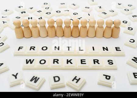 Frontline Workers Worte mit Linie von hölzernen Peg Puppe Figuren Auf weißem Hintergrund Stockfoto