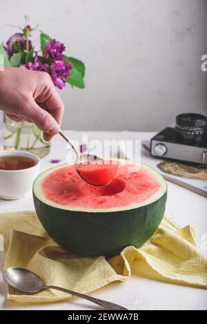 Der Löffel mit Stück Wassermelone in man Hand Stockfoto
