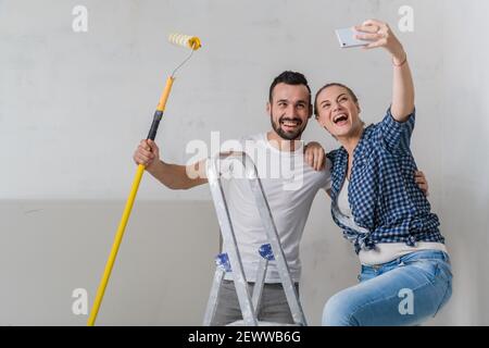 Ein Ehepaar macht ein Selfie am Telefon, während sie Reparaturen machen, lächeln sie Stockfoto