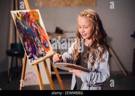 Junge Mädchen kreative Künstlerin bei der Arbeit in einem Workshop. Mit Leidenschaft zeichnet ein Bild in die Arbeit eingetaucht. Stockfoto