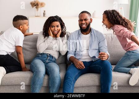 Böse schwarze Kinder kämpfen um ihre schockierten Eltern Stockfoto