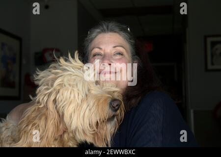 Milton, GA, USA. März 2021, 3rd. Jennifer Arnold mit Great, eine 4-jährige Golddoodle, die gelehrt wird, zu schnüffeln und zu unterscheiden biochemische Reaktionen min eine Person, die mit COVID-19 infiziert wurde. Canine AssistantsÃ 'Medical Detection Hunde verwenden diese Art von Alarm, bekannt als Nasenpunkt-Indikator, um binäre Fragen wie "Riechen Sie Ihren Zielgeruch zu beantworten? Ja oder Nein?’’’ Arnold erklärt. Ihr Unternehmen, das Servicehunde ausbildet, um Menschen mit medizinischen Bedürfnissen zu helfen, lehrt sie nun, das Coronavirus in älteren Lebensgemeinschaften aufzuspüren. Kredit: ZUMA Press, Inc./Alamy Live Nachrichten Stockfoto