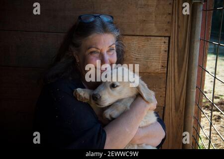 Milton, GA, USA. März 2021, 3rd. Die Gründerin von Canine, Jennifer Arnold, kuschelt sich Mayberry, ein 12 Wochen alter Golden Retriever Welpe, auf ihrer Trainingsfarm in Nord-Georgia AssistantsÃ. "Welpen entwickeln Vertrauen in die Menschen und Vertrauen in sich selbst als Teil unseres Bildungsprotokolls bekannt als Bond-basierte Ansatz", sagte sie. Diese Zukunft Medical Alert Hunde begann die 18-24 Monate Bildungsprozess bei 5 Wochen Alter. Kredit: ZUMA Press, Inc./Alamy Live Nachrichten Stockfoto