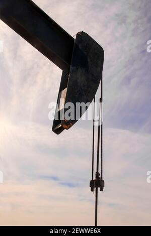 Fast abgeschliffter Kopf der Ölbrunnen-Pumpenheber gegen ein Ziemlich trüber blauer und violetter Himmel Stockfoto