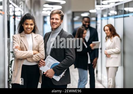 Porträt von freundlichen, multiethnischen Kollegen im modernen Büro. Erfolgreiche glückliche Geschäftsleute lächeln, auf die Kamera schauen, zusammenarbeiten, Partnerschaftskonzept Stockfoto