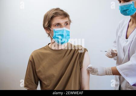 Mann erhält Covid-19-Impfstoff. Nahaufnahme Arzt macht Injektion an den Patienten in medizinische Maske. Spritze mit Coronavirus-Impfstoff. Der Mann erhält eine Jab-Impfung Stockfoto