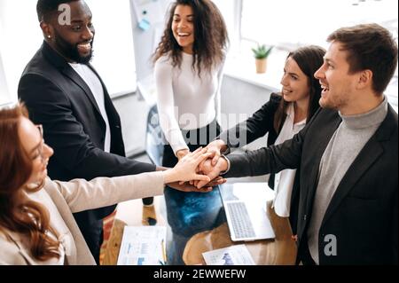 Tolle Teamarbeit. Mixed-Rennen erfolgreiche Business-Team, legt ihre Hände zusammen über einen Arbeitsplatz in ihrem modernen kreativen Büro, genießen Sie einen guten Job. Einheit und Teamwork Konzept Stockfoto