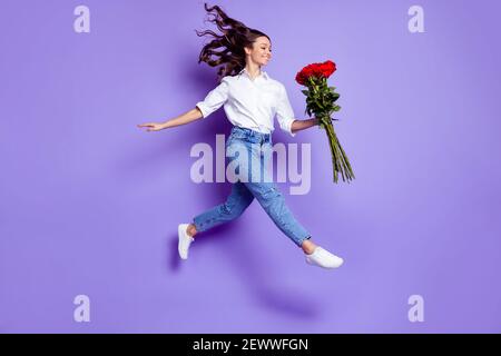 Profilfoto der inspirierten Dame springen halten Bouquet gehen tragen Weißes Hemd isoliert violette Farbe Hintergrund Stockfoto