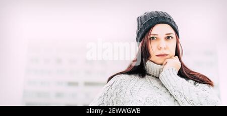Portrait der jungen Frau in grau gestrickt Pullover und Hut. Nahaufnahme von hübschen weiblichen Posen und Blick auf die Kamera Stockfoto