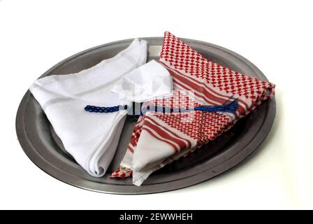 Arabisches traditionelles Bekleidungszubehör genannt Shemagh, weißer Ghutrah, weiße islamische Kappe und Rosenkranz isoliert in Tablett auf weißem Hintergrund Stockfoto