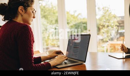 Frau am Tisch sitzend, die auf dem Laptop tippt. Schriftstellerin, die von zu Hause aus arbeitet. Stockfoto