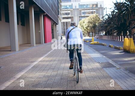 Rückansicht des afroamerikanischen Senioren, der Fahrrad fährt Die Straße Stockfoto