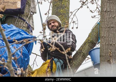 York Gardens, London, Großbritannien. 3. März 2021. Marcus Decker, 33, in der Nähe des Banners der Baumschutzkampagne, an der er teilnimmt. Es ist der zehnte Tag des Baumpflegesitzens für die Erdenschützer, die einen 100 Jahre alten schwarzen Pappelbaum besetzen, der am Montag, den 22. Februar 2021, von einem Joint Venture zwischen Taylor Wimpey Homes und dem Rat von Wandsworth gefällt werden soll. Kredit: SABRINA MEROLLA/Alamy Live News Stockfoto