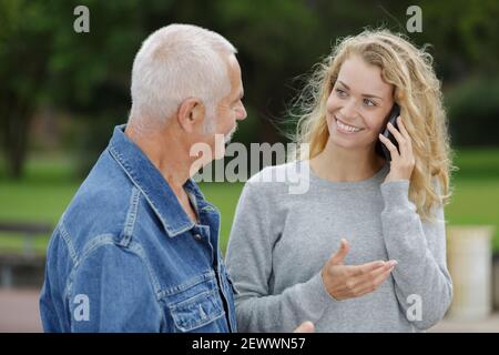 Lächelnde junge Frau auf Handy mit älteren Vater Stockfoto