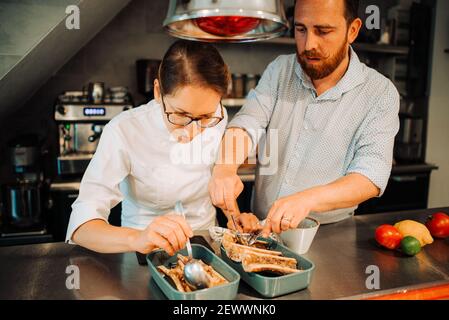 Ein paar Köche arbeiten zusammen, während sie Essen im Restaurant zubereiten Stockfoto