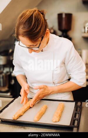 Frau Koch Putting Teig auf Tablett, um Kekse zu backen Stockfoto