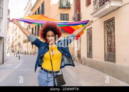 Frau mit afro Haar trägt Homosexuell Stolz Flagge Stockfoto